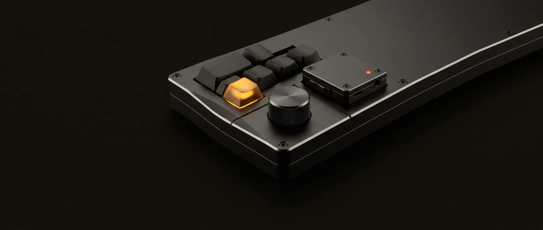 Matte black keyboard with one amber backlit keycap beside a machined knob and a compact recorder module